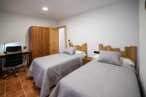 two beds in a room with a desk and a computer at Apartamento Monte Mar 1 in Haza del Trigo
