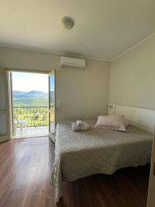 a bedroom with a large bed and a balcony at Residencial Encantos Linha Bonita - Vista que acalma, ambiente que encanta! in Gramado