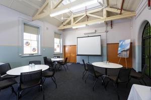 a classroom with tables and chairs and a whiteboard at YHA Fremantle Prison in Fremantle