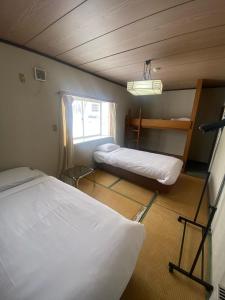 a small room with two beds and a window at Hakuba Cortina Backpackers in Otari