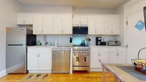 a kitchen with white cabinets and stainless steel appliances at Renovated, Spacious Studio, Near Bc, Bu, Porch in Boston