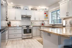 Una cocina con gabinetes blancos y electrodomésticos de acero inoxidable. en River Meadows Pool Hot Tub - Deschutes Riverhaus, en Bend