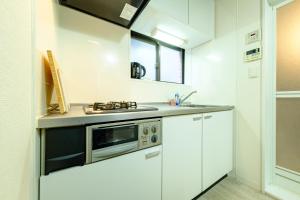 a white kitchen with a sink and a microwave at CREARE Residence Kagurazaka - クレアーレ神楽坂ゲストハウス105号室 in Tokyo +46 photos