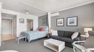 a living room with a bed and a couch at Panorama Daze Ettalong Beach in Ettalong Beach