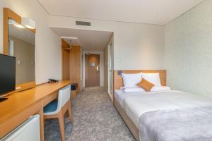 a hotel room with a bed and a desk and a television at Art Hotel Niigata Station in Niigata