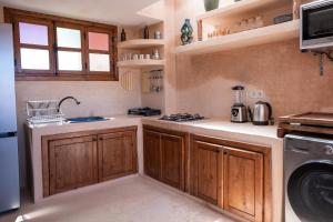 a kitchen with wooden cabinets and a washer and dryer at The Cove Surf House in Tamraght Ouzdar