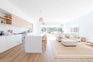 a white kitchen and living room with a couch and a table at Torquay Beach Getaway in Torquay