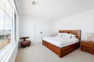 a white bedroom with a bed and a window at Torquay Beach Getaway in Torquay