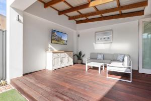 ein Wohnzimmer mit Sofa und Tisch in der Unterkunft Bluestone Symmetrical Cottage with Outdoor Area in North Adelaide