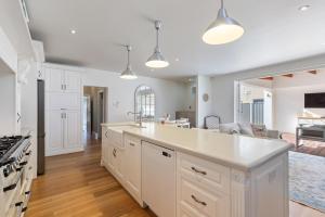 eine Küche mit weißen Schränken und einer großen Insel in der Unterkunft Bluestone Symmetrical Cottage with Outdoor Area in North Adelaide