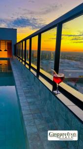 a glass of wine sitting on the edge of a swimming pool at Gasparetour Flat - em frente ao Shopping Estação in Cuiabá