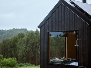 una pequeña casa negra con una gran ventana en Ocean View Off-Grid Cabin Secluded in Nature - Govind, en Johanna