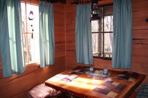 Zimmer mit einem Holztisch in einer Hütte mit Fenstern in der Unterkunft Wombat Cabin in Moina