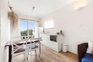 a kitchen with a table and chairs in a room at Quay's Cabin - Absolute Beachfront with Views in Callala Beach