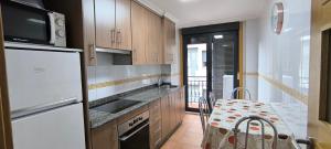 a kitchen with a white refrigerator and a table at Apartamento A Cañiza in La Cañiza