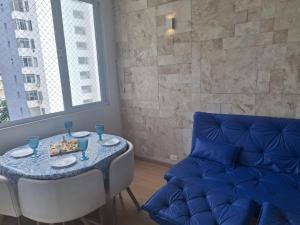 a dining room with a table and a blue couch at Beach House 2 in Guarujá