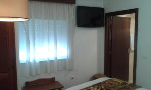 a bedroom with a bed and a television on the wall at Hotel Tic Tac in Bragança