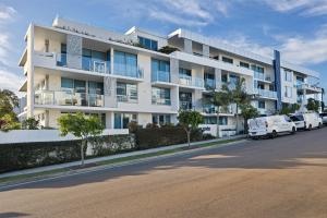 a white building with cars parked in front of it at Elysee Beachside Apartments Alexandra Headland in Alexandra Headland