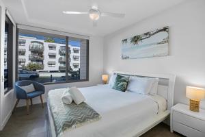 a white bedroom with a bed and a window at Elysee Beachside Apartments Alexandra Headland in Alexandra Headland +41 photos