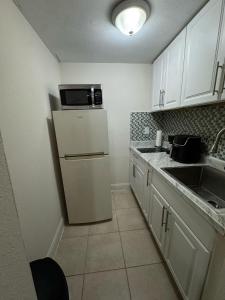 a small kitchen with a refrigerator and a sink at Pacifica Blue Ocean in Dania Beach