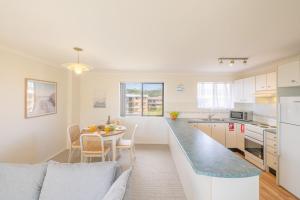 a kitchen and living room with a table and a counter at Intrepid 12 right on the beachfront in Shoal Bay