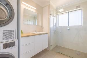a bathroom with a shower and a sink and a washing machine at Intrepid 12 right on the beachfront in Shoal Bay