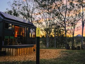 una pequeña casa negra en un campo con la puesta de sol en Secluded & Pet Friendly Cabin Deep in Nature - Remy, en Coleyville