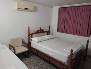 a bedroom with a bed and a chair and a window at Tranquila y cerca de la magia in Cartagena de Indias