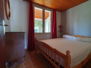 a bedroom with a bed and a window with red curtains at Maison spacieuse 6 pers. près plage avec jardin - FR-1-476-204 in La Faute-sur-Mer