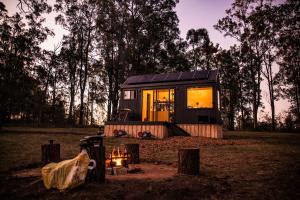 a tiny house sitting in a field with a fire at Off-Grid Cabin in the Hunter Valley - Hazel in Pokolbin