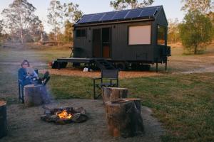 una mujer sentada junto a una fogata con un remolque en Secluded & Pet Friendly Cabin Deep in Nature - Zerya, en Coleyville