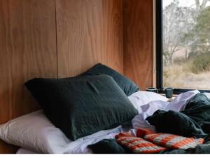 Cama con almohada y ventana en una habitación en Secluded & Pet Friendly Cabin Deep in Nature - Zerya, en Coleyville