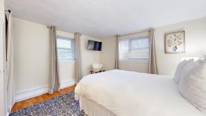 a bedroom with a white bed and two windows at Boston Vacation,longwood Medical,mins To Mbta,pkg in Brookline +5 photos