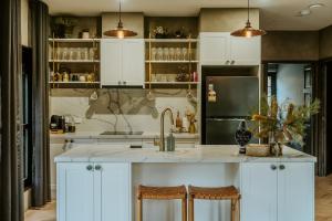 a kitchen with white cabinets and a kitchen island with stools at The Temple - Country Farm Retreat in Launching Place +71 photos