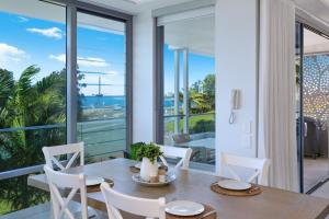 a dining room with a table and views of the ocean at Elysee Beachside Apartments Alexandra Headland in Alexandra Headland