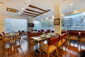 a restaurant with wooden tables and chairs and large windows at OPO Premier, GK2 in New Delhi