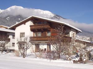 a house in the snow with a snow covered mountain at Haus Wiesengrund in Fulpmes