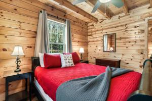 ein Schlafzimmer mit einem roten Bett in einer Blockhütte in der Unterkunft Woodland Ridge - Private 3 Bedrooms with Hot Tub in Sevierville