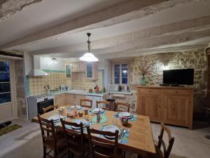una cucina con tavolo, sedie e televisione di Maison familiale avec piscine privée, jeux pour enfants, salle de sport et Wifi en Dordogne - FR-1-616-70 a Cherveix-Cubas