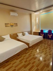 a hotel room with two beds and a table and chairs at thieuki 1 in Hà Tĩnh
