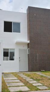 un edificio blanco con una puerta blanca y una pared de ladrillo en casa kiwi playa del carmen, en Playa del Carmen