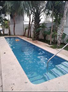 una piscina con agua azul y palmeras en casa kiwi playa del carmen, en Playa del Carmen 4 fotos más