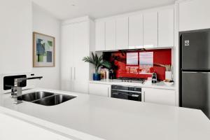 a white kitchen with a sink and a refrigerator at Zen Grand 3 Bedroom Residences 120m2 with up to 7 Separate Beds in Melbourne +38 photos