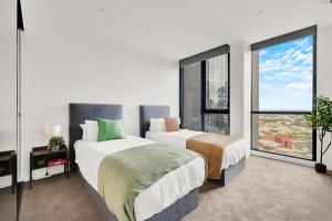 a bedroom with two beds and a large window at Zen Grand 3 Bedroom Residences 120m2 with up to 7 Separate Beds in Melbourne