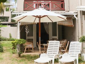 a group of chairs and an umbrella on a patio at Villa Beach Retreat plage à 1mn grand jardin tropical piscine à débordement in Bain Boeuf