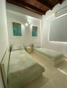 a bedroom with two beds and a window at Casa Española del Mar in Cartagena de Indias