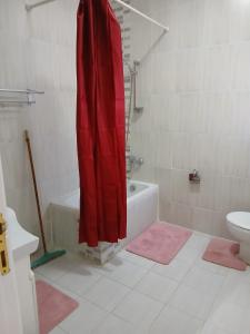 a bathroom with a red shower curtain and a toilet at Cozy Villa in Hurghada