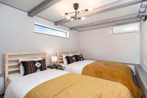 two beds in a room with white walls and windows at Villa Gotemba Fuji in Gotemba