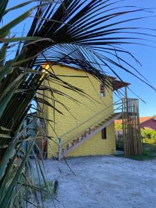 a yellow building with a staircase on the side of it at Sol Suítes Caraíva in Porto Seguro