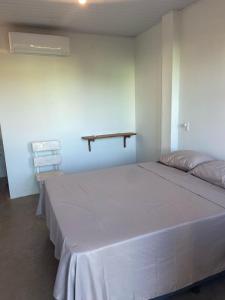 a bedroom with a large bed and a shelf on the wall at Sol Suítes Caraíva in Porto Seguro